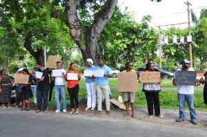 Persons gather outside of the Legal Affairs Ministry to protest the killing of Crum-Ewing