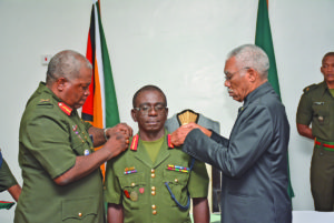 Colonel George Lewis receiving the badge of rank of Brigadier from his predecessor Brigadier Mark Phillips and the  Commander-in-Chief of the Armed Forces, President David Granger